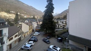 A parking lot with several cars, a large evergreen tree, and buildings in the background.