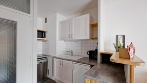 Een moderne keuken met witte kastjes, een granieten aanrecht en een koffieapparaat.