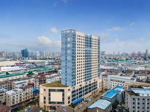 A high-rise hotel with multiple floors, surrounded by other buildings and a clear sky.