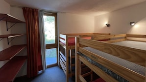 Um dormitório com beliches, uma janela com cortinas e um pequeno armário.