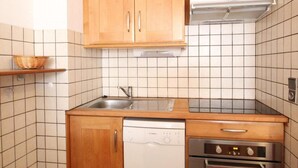 A compact kitchen with wooden cabinets, a built-in dishwasher, a stainless steel oven, and a tiled backsplash. - 300m from ski slopes, 1st floor, balcony, tv, ski locker, 41m², Val Cenis (Lanslebourg-Mont-Cenis)
