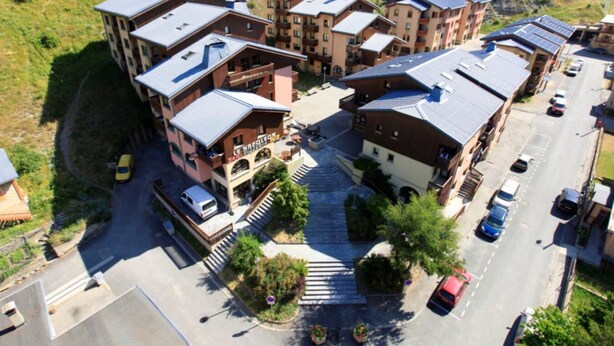 A multi-story hotel with a central courtyard, surrounded by parking and roads. - 300m from ski slopes, 1st floor, balcony, tv, ski locker, 41m², Val Cenis (Lanslebourg-Mont-Cenis)