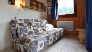 A cozy room with a wooden sofa, a wall-mounted shelf, and a window with a view of trees. - Floor -1, terrace, tv, ski locker, 25m², Val Cenis (Lanslevillard)