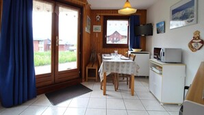 A cozy room with a wooden interior, a dining table set for two, a television, and a view of a red building outside. - Floor -1, terrace, tv, ski locker, 25m², Val Cenis (Lanslevillard)