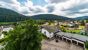 Un quartier résidentiel avec des maisons, une église et un grand arbre au premier plan.