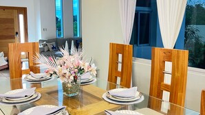 A modern dining area with a glass table, wooden chairs, and a vase of flowers.