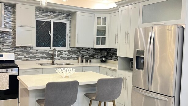 A modern kitchen with a central island, stainless steel appliances, and pendant lighting.