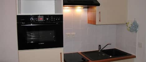 A compact kitchen with a Bosch oven, a sink, and wooden countertops.