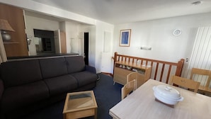 A compact living space with a sofa, a dining table with chairs, a small kitchen area, and a visible door. - 150m from ski slopes, 3rd floor, view resort, fitness, swimming pool, sauna, tv, ski locker, 35m² (Eaux-Bonnes)