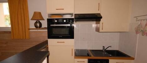 A compact kitchen with a stove, oven, sink, and dishwasher.