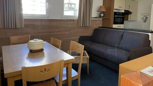 A compact living space with a dining table, chairs, a sofa, and a kitchenette. - 150m from ski slopes, 3rd floor, view resort, fitness, swimming pool, sauna, tv, ski locker, 35m² (Eaux-Bonnes)
