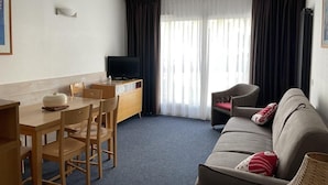 Una camera d'albergo compatta con zona pranzo, divano e televisore.