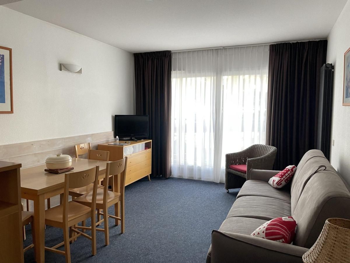 Une chambre d’hôtel de taille réduite comprenant un coin repas, un canapé et un téléviseur.