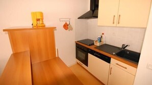 A compact kitchen with a stove, oven, and sink. There is a wooden counter and a yellow appliance on top. - 150m from ski slopes, 2nd floor, view ski slopes, fitness, swimming pool, sauna, tv, ski locker (Eaux-Bonnes)
