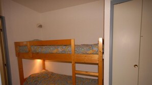 Una cama litera con ropa de cama estampada en una habitación con una puerta y un accesorio de iluminación en la pared.