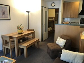 Un espacio habitable compacto con una mesa de comedor, un sofá, una banca y una kitchenette.