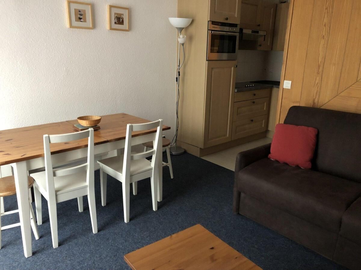 A compact living space with a dining area, a sofa, and a kitchenette.