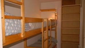 Une chambre avec un lit superposé, une échelle en bois et une petite étagère.