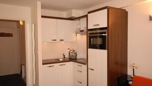 A compact kitchen with white cabinets, a built-in oven, and a sink. - 30m from ski slopes, 1st floor, view ski slopes, tv, 24m², Gourette (Eaux-Bonnes)