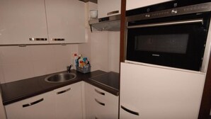 A modern kitchen with white cabinets, a stainless steel sink, and a built-in oven. - 30m from ski slopes, 1st floor, view ski slopes, tv, 24m², Gourette (Eaux-Bonnes)