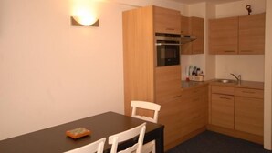 Eine kleine Küche mit Holzausstattung, einem eingebauten Backofen und einer Arbeitsplatte.