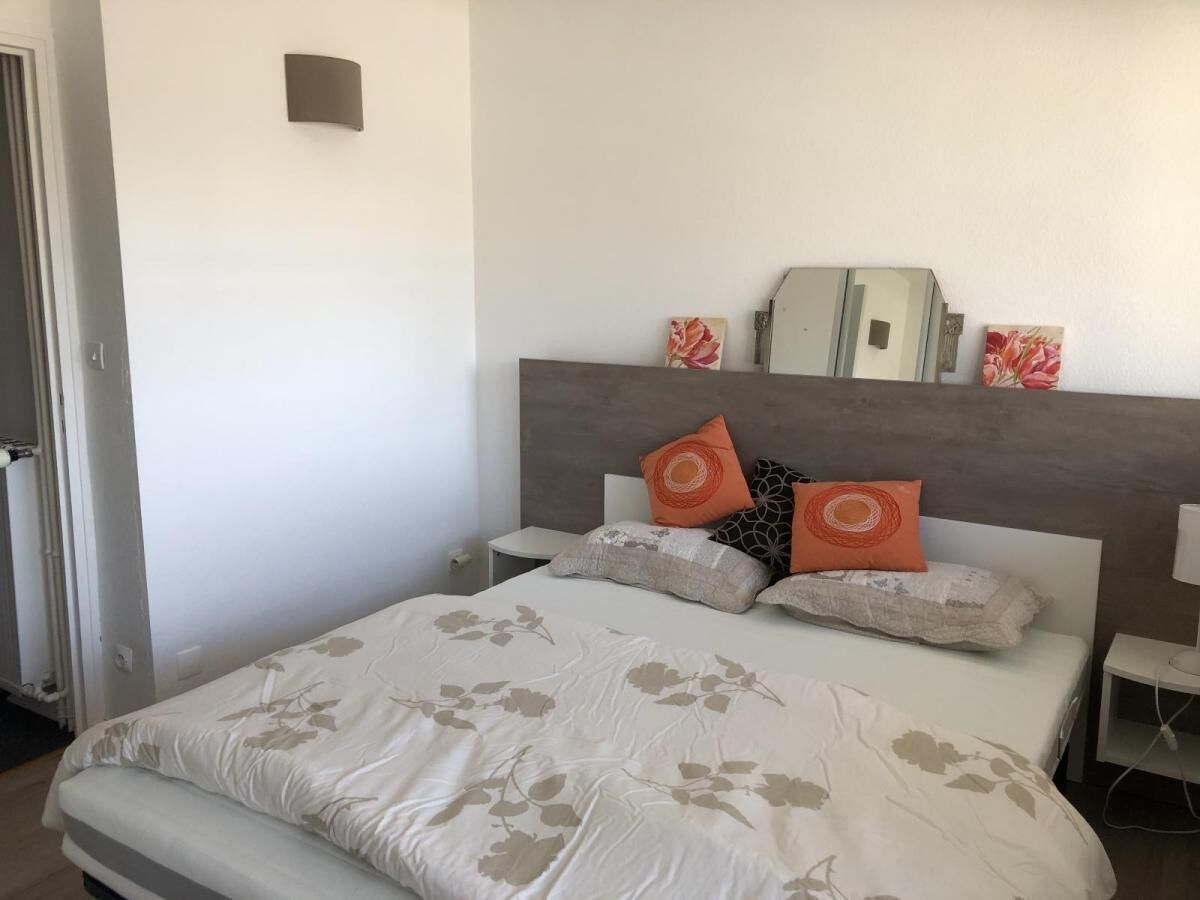 A bedroom with a bed, nightstands, and a mirror.