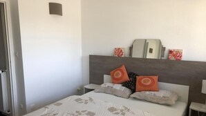 Une chambre à coucher avec un lit, des tables de chevet et un miroir.