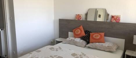 A bedroom with a bed, nightstands, and a mirror.