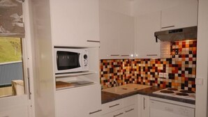 Une cuisine avec des meubles blancs, un four à micro-ondes, un pare-feu en carrelage et une cuisinière.