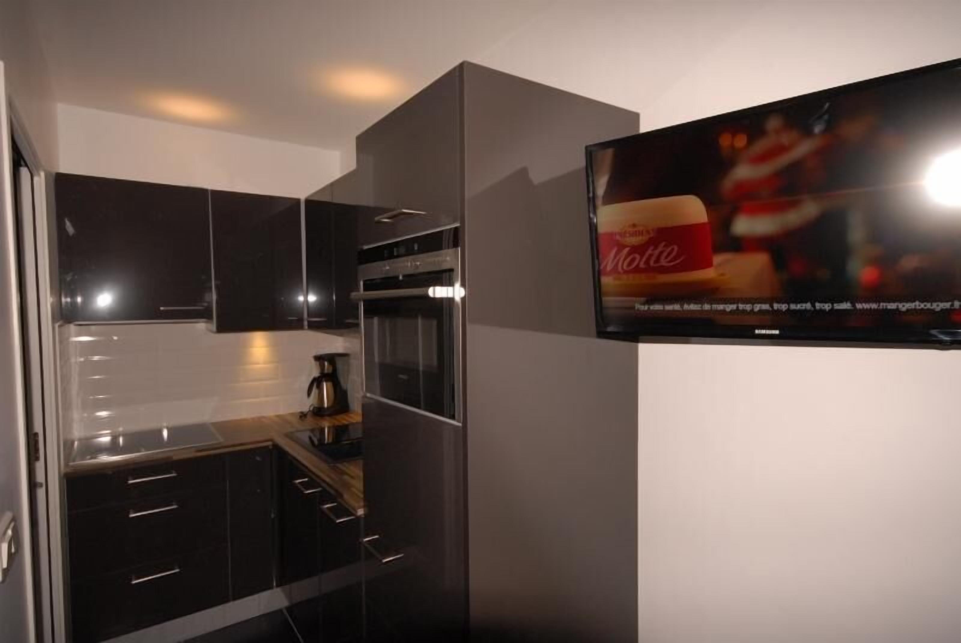 A modern kitchen with dark cabinetry, a stainless steel oven, and a coffee maker.