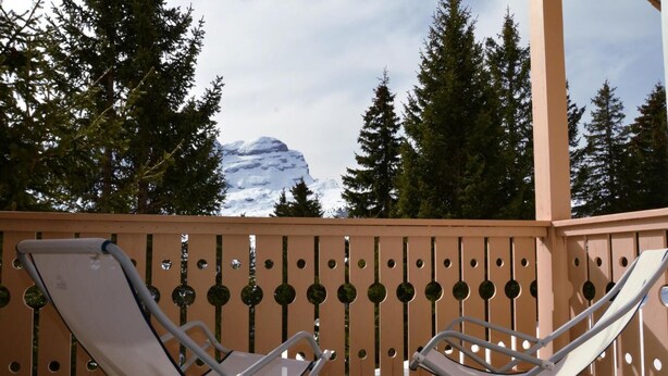A balcony with two white lounge chairs and a wooden railing with circular cutouts. - 1st floor, balcony, tv, ski locker, 75m², Flaine (Flaine)