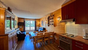 A cozy cabin interior with a dining area, kitchen, and a large window with a view. - 1st floor, balcony, tv, ski locker, 75m², Flaine (Flaine)