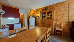 A compact kitchen with wooden cabinets, a dining table, and chairs. - 1st floor, balcony, tv, ski locker, 75m², Flaine (Flaine)