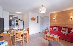 A compact living space with a kitchenette, dining area, and a red sofa with decorative pillows. - Resort center, swimming pool, tv, ski locker, 38m², Les 2 Alpes (Les Deux Alpes)