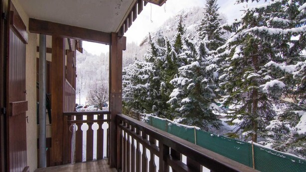 A balcony with a view of snow-covered trees.