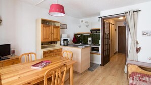 A compact kitchen with wooden cabinets, a dining table, and a red pendant light.