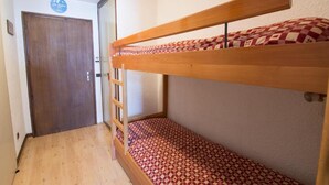 A bunk bed room with a wooden ladder, a patterned mattress, and a door with a sign above it.