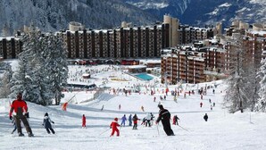 Ein Skigebiet mit mehreren Gebäuden, einer Skipiste und einem Poolbereich.