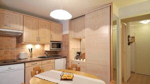 Une cuisine compacte dotée de meubles en bois, d’un four à micro-ondes, d’un grille-pain et d’une machine à café.