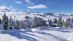 Un paysage de montagne enneigé, avec un chalet et des traces de ski.