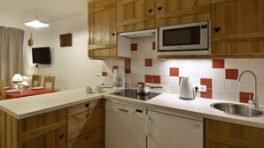 Una cucina compatta con mobili in legno, un forno a microonde, una macchina da caffè e una lavastoviglie.