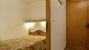 Una camera da letto piccola con un letto singolo, una porta in legno e un lampadario a parete.