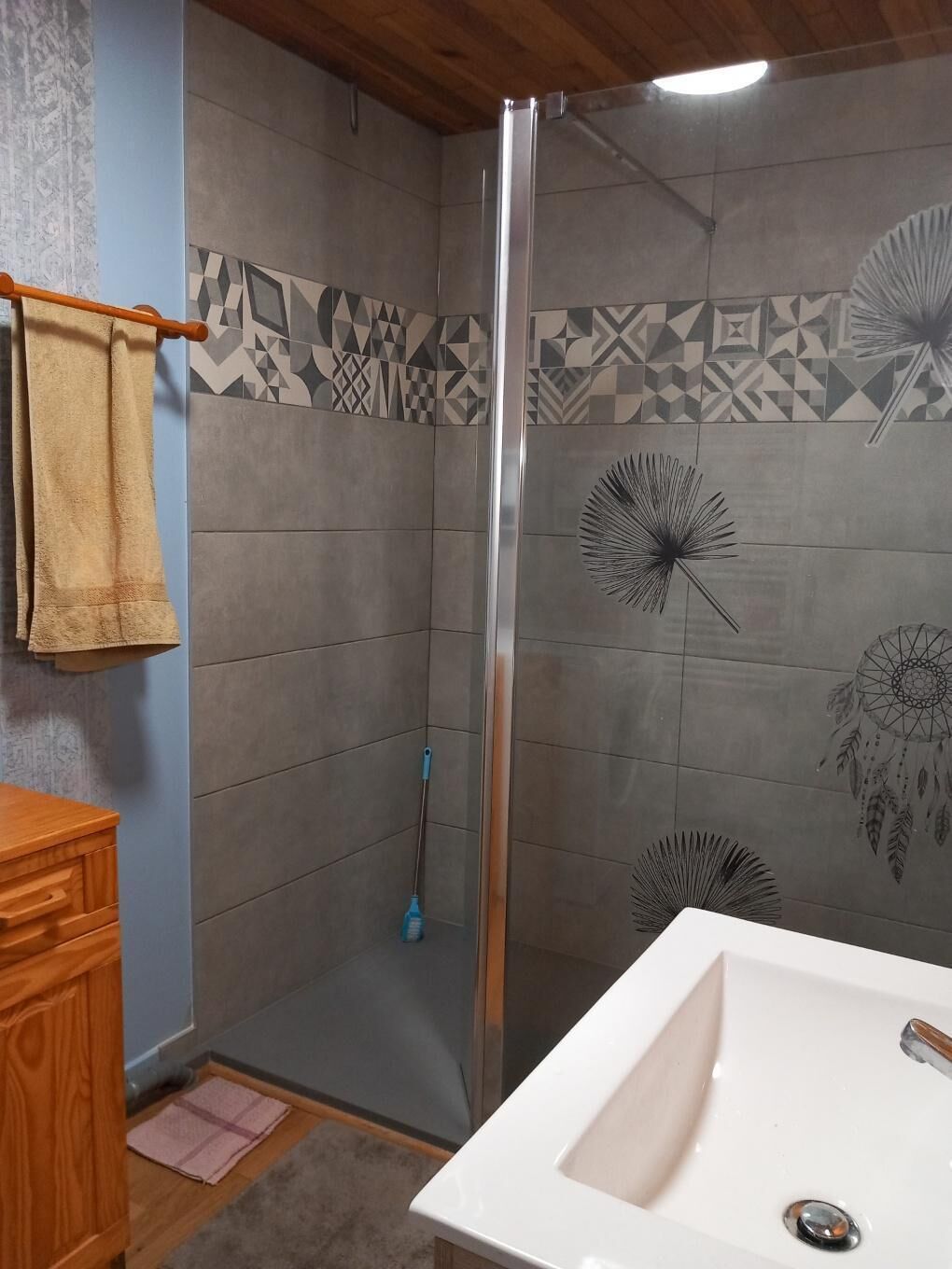 Un baño con ducha, lavamanos y azulejos con diseño.