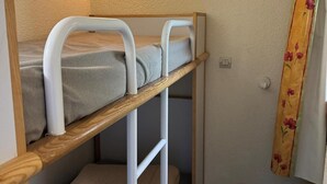 Ein Stockbett mit Holzrahmen und weißen Metallgeländern.