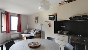 A compact living space with a sofa bed, a dining table, a microwave, a stove, and a small kitchen area. - 20m from ski slopes, Ground floor, view ski slopes, tv, 40m², La Plagne (La Plagne)
