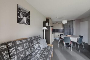 Ein gemütlicher Wohnraum mit einer Couch, einem Esstisch und einer Küchenzeile.