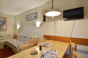 A cozy room with a wooden dining table, a sofa, and a TV mounted on the wall. - Ski-in/ski-out & foot of the slopes, 7th floor, view ski slopes/ski slopes, balcony, tv, 28m² (La Plagne)