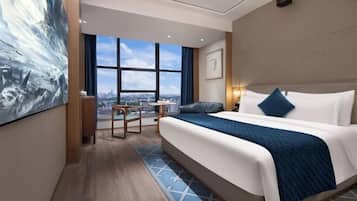 Ein modernes Hotelzimmer mit einem großen Bett, einem Schreibtisch und Blick auf die Stadt.