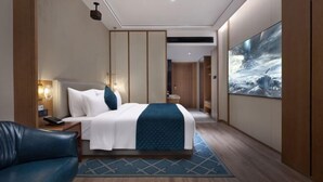A modern hotel room with a large bed, a desk, a chair, and a large painting on the wall. - Xiangtan Manqi Hotel (Xiangtan)