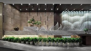 A modern reception area with a marble counter, potted plants, and a water feature. - Xiangtan Manqi Hotel (Xiangtan)